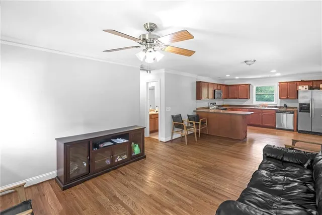 a living room with stainless steel appliances furniture a fireplace and wooden floor