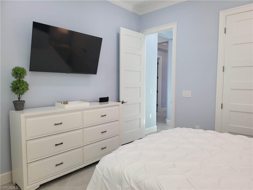 8920 Calypso Court Naples, FL 34113 - Photo 17 of 41 a bedroom with a bed and a flat screen tv