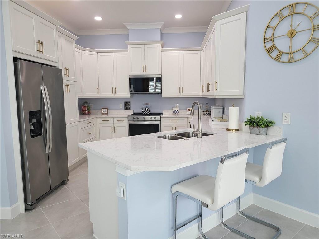 8920 Calypso Court Naples, FL 34113 - Photo 8 of 41 a kitchen with stainless steel appliances granite countertop a sink a stove a refrigerator and a refrigerator with wooden floor