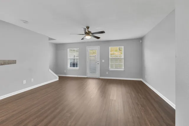 a view of an empty room with window and wooden floor