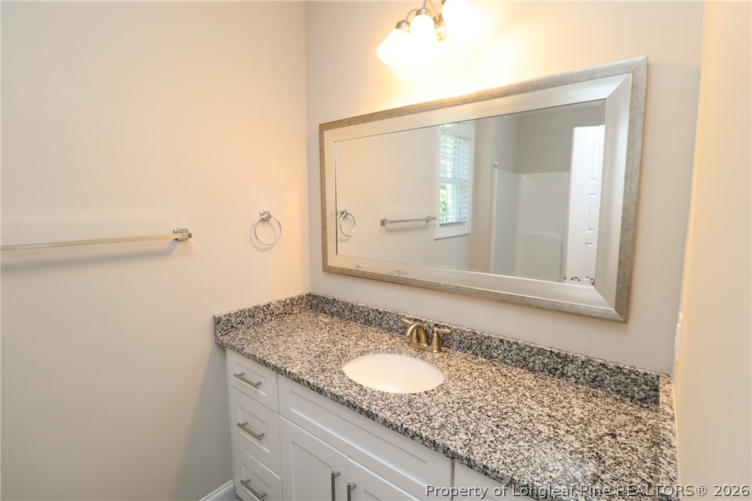 8424 Rhodes Road Apex, NC 27539 - Photo 27 of 31 a bathroom with a granite countertop sink and a mirror