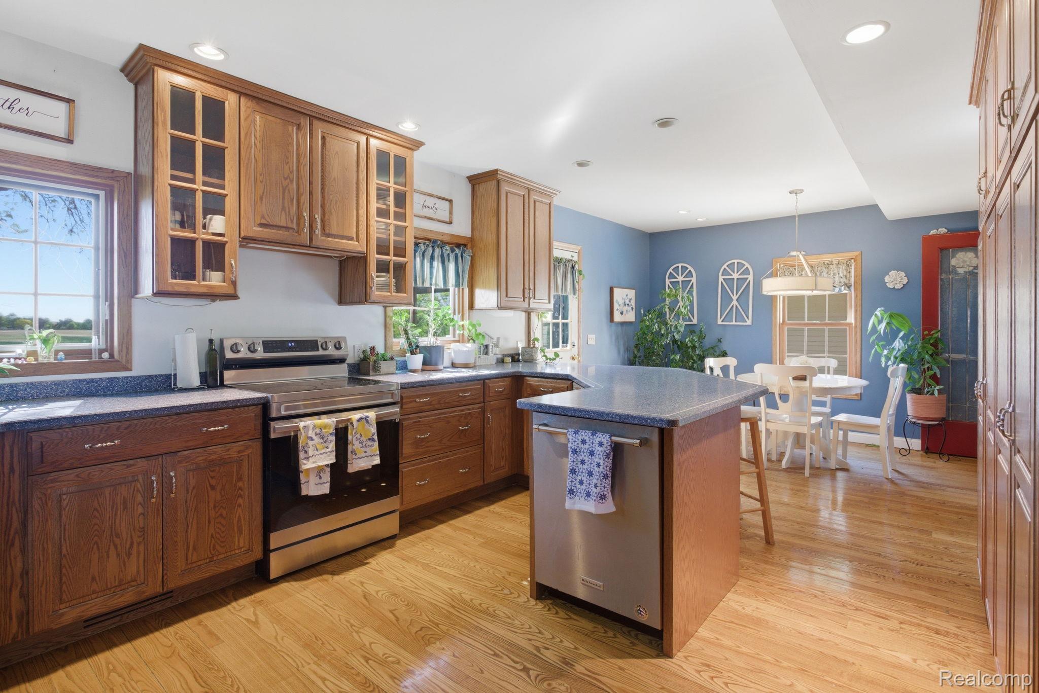 14104 Carleton West Road Carleton, MI 48117 - Photo 21 of 58 Kitchen featuring stainless steel appliances, a kitchen bar, light wood-type flooring, glass insert cabinets, and a kitchen island