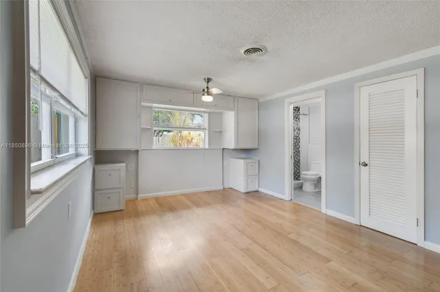 a view of empty room with wooden floor and fan