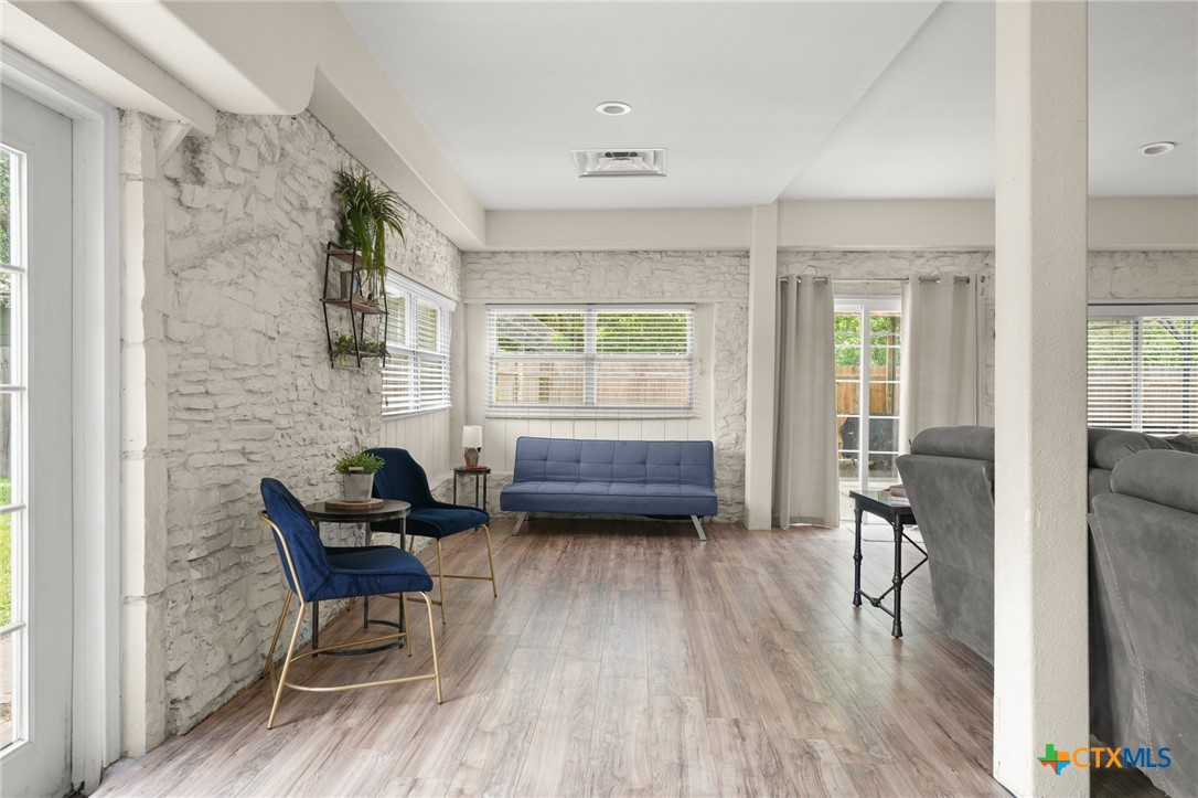 9725 Bock Road Buda, TX 78610 - Photo 13 of 37 Whitewashed stone walls and light-toned wood-look flooring establish a relaxed ambiance in this casual gathering area.