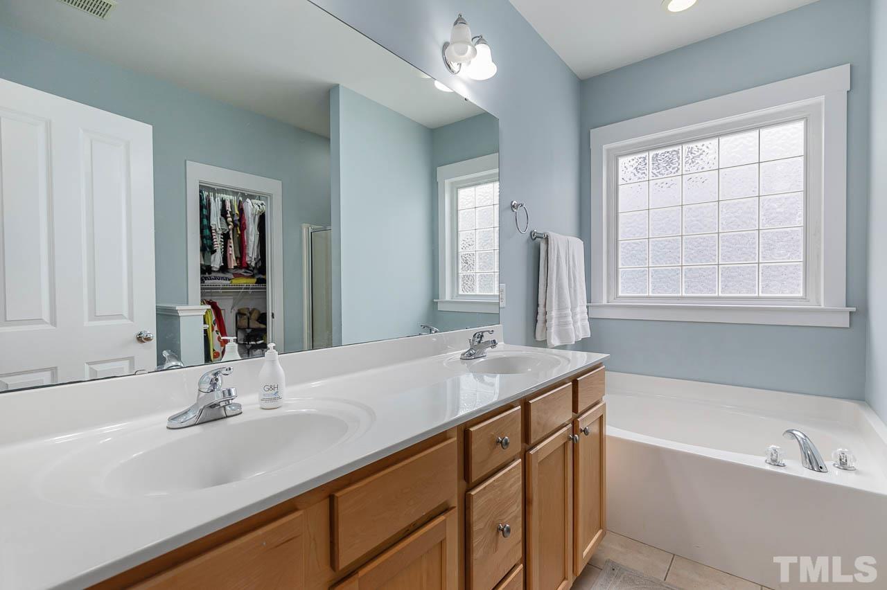 2813 Falls River Avenue Raleigh, NC 27614 - Photo 12 of 28 a bathroom with a sink tub double vanity and a mirror