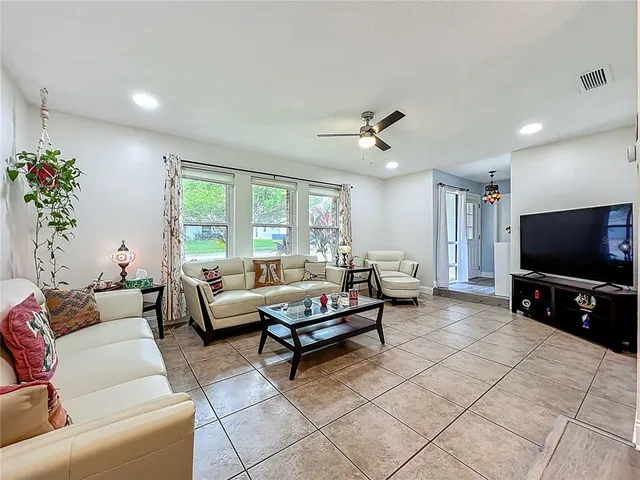 a view of a dining room and livingroom with furniture wooden floor a rug and a chandelier