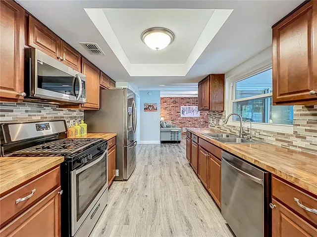 a kitchen with stainless steel appliances a refrigerator and wooden floor