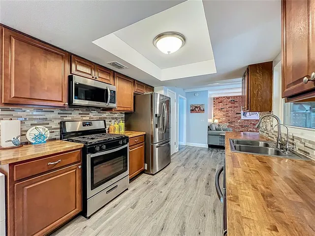 a large living room with stainless steel appliances kitchen island granite countertop wooden cabinets a couch and a view of living room