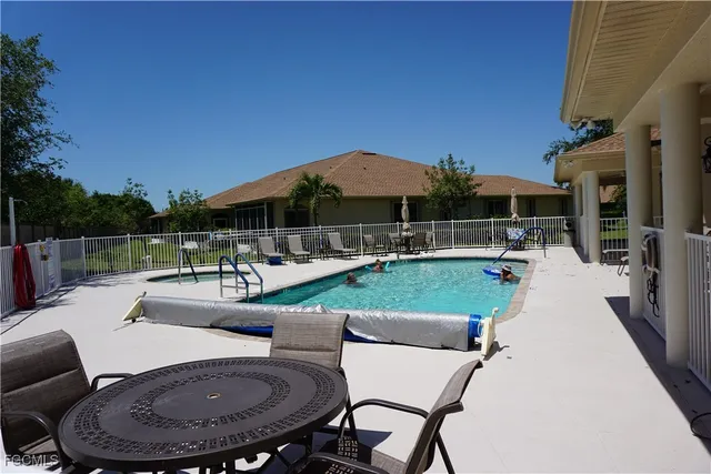a view of a patio with couches table and chairs under an umbrella with a fire pit