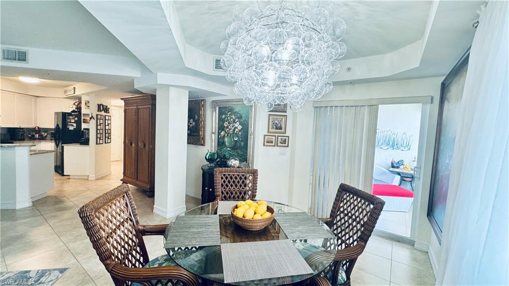 Tiled dining area with a raised ceiling and an inviting chandelier