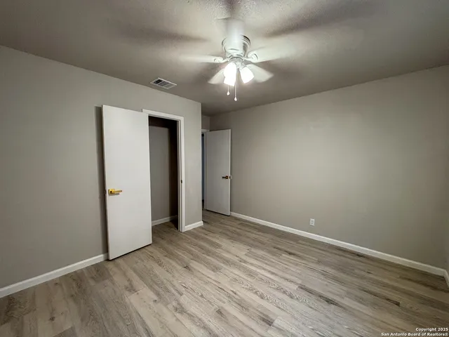 an empty room with wooden floor and chandelier fan