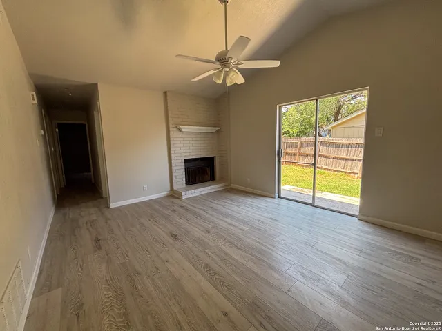 a view of an empty room with a window and wooden floor