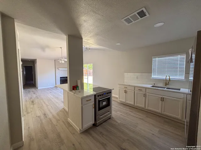 a kitchen with granite countertop a stove top oven sink and cabinets