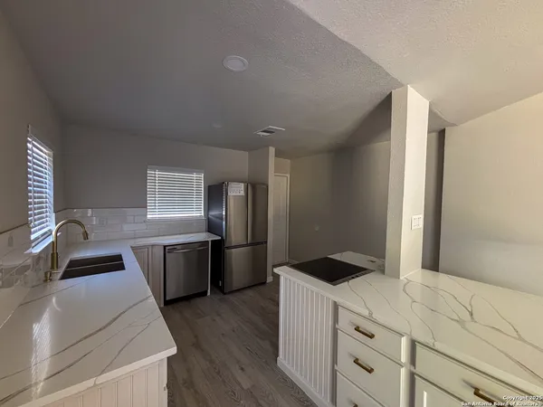 a kitchen with granite countertop a refrigerator stove and sink