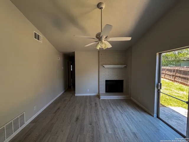 a view of an empty room with a window and wooden floor