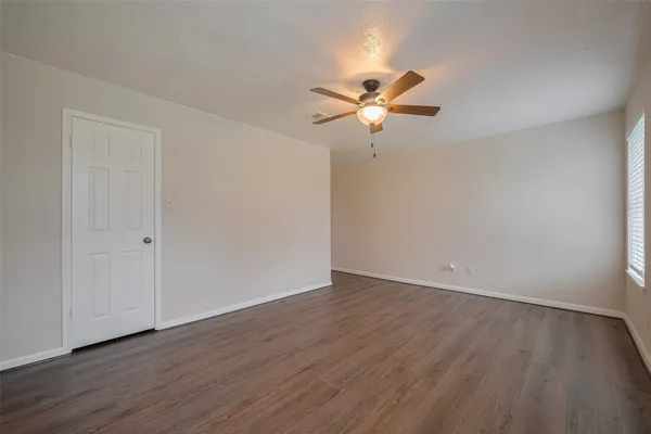 a view of a room with wooden floor and a ceiling fan