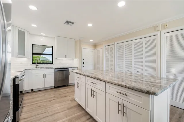 a kitchen with stainless steel appliances granite countertop a refrigerator and a stove top oven