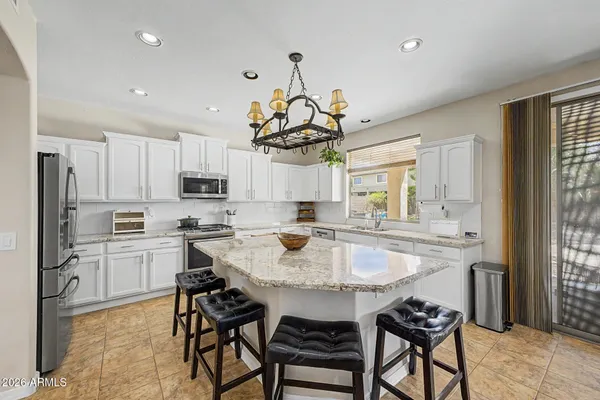 a kitchen with stainless steel appliances kitchen island granite countertop a sink and a refrigerator