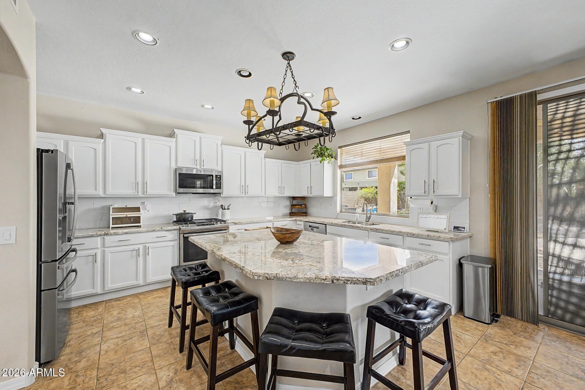 3595 East Latham Way Gilbert, AZ 85297 - Photo 11 of 35 a kitchen with stainless steel appliances kitchen island granite countertop a sink and a refrigerator