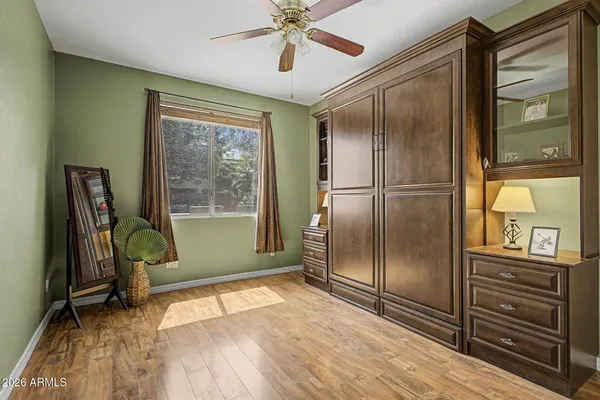 a view of a refrigerator in kitchen and an empty room wooden floor fan