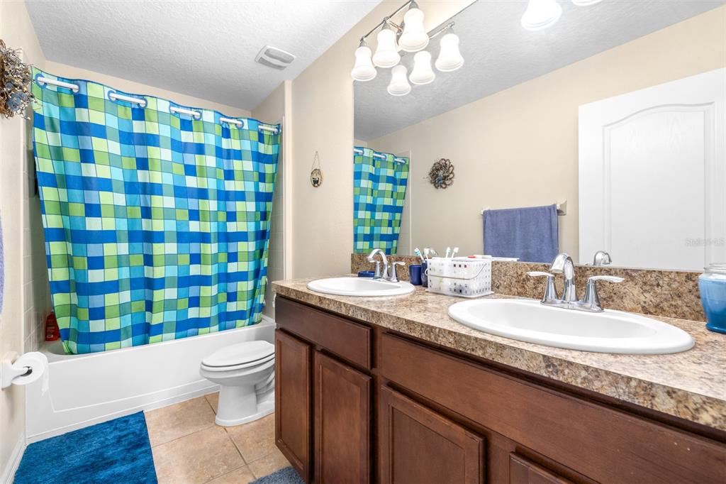 1564 Imperial Key Drive Trinity, FL 34655 - Photo 27 of 40 a bathroom with a granite countertop sink a toilet a mirror a bathtub and shower