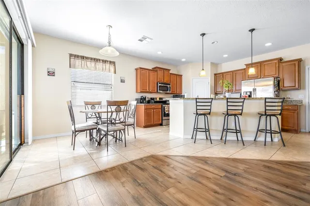 a kitchen with stainless steel appliances kitchen island granite countertop a stove a sink a dining table and chairs