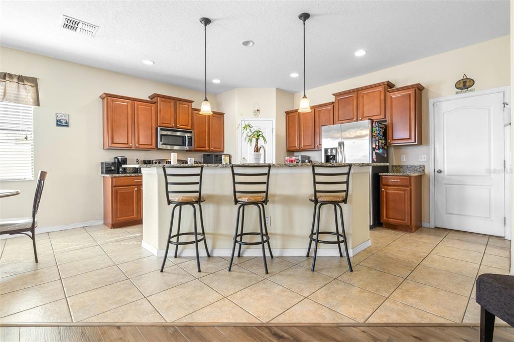 1564 Imperial Key Drive Trinity, FL 34655 - Photo 7 of 40 a kitchen with stainless steel appliances kitchen island granite countertop a stove a sink a dining table and chairs