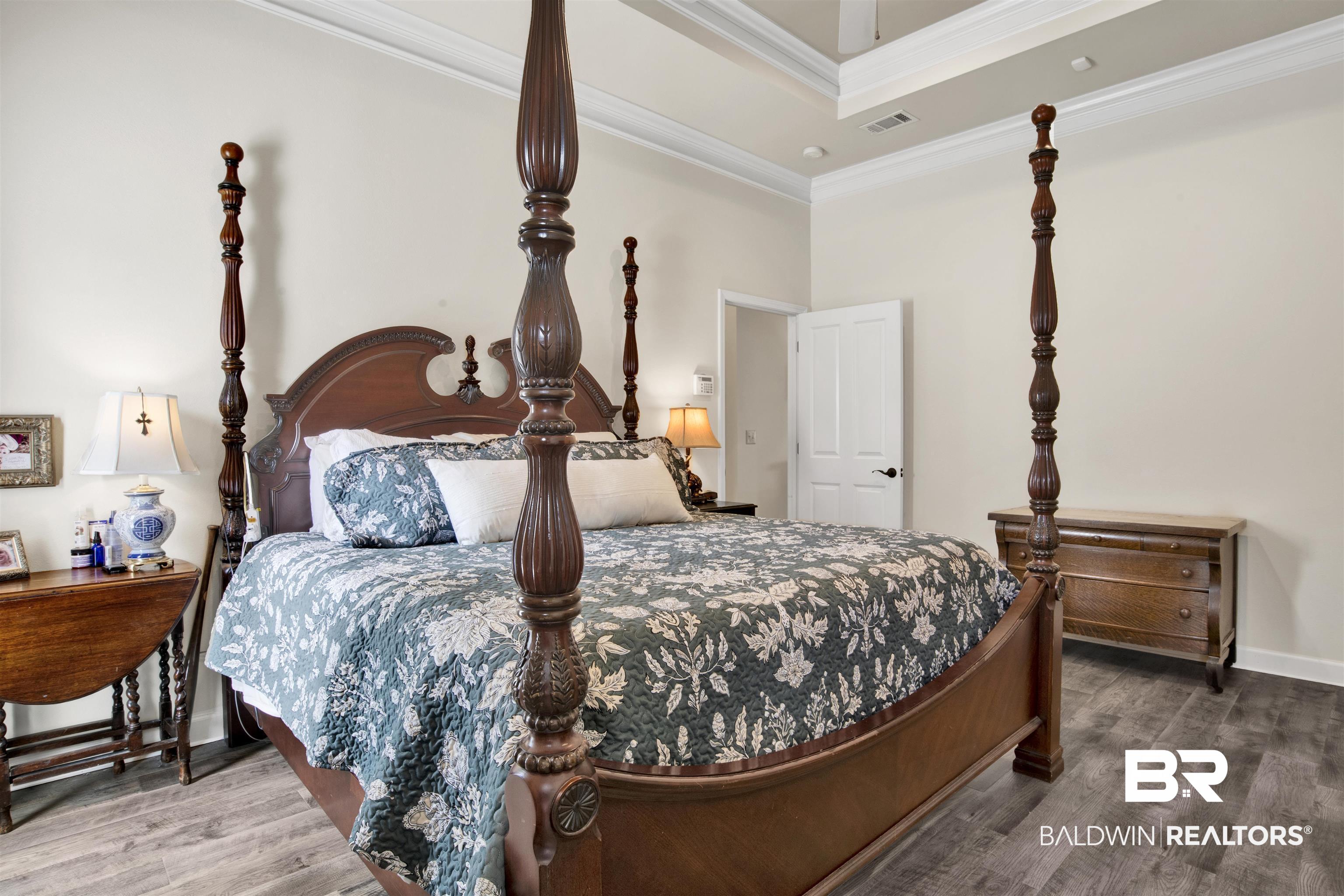 10368 Gayfer Rd Extension Fairhope, AL 36532 - Photo 21 of 43 Spacious bedroom featuring wood-finish flooring, a tray ceiling, crown molding, and a white paneled door