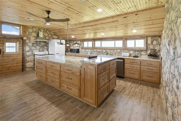 a kitchen with stainless steel appliances kitchen island granite countertop a table chairs in it and wooden floors
