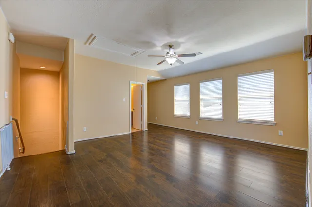 a view of an empty room with a window and wooden floor