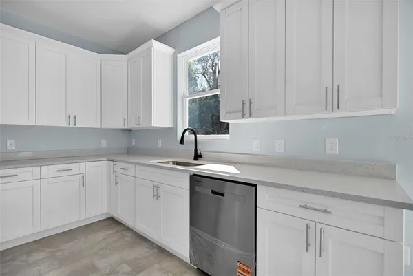 a kitchen with white cabinets and sink