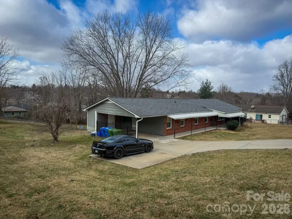 a view of a house with a yard covered in the forest