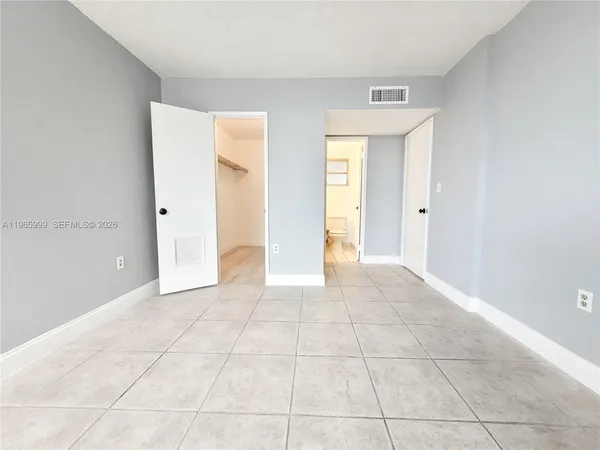 a view of an empty room with window and bathroom