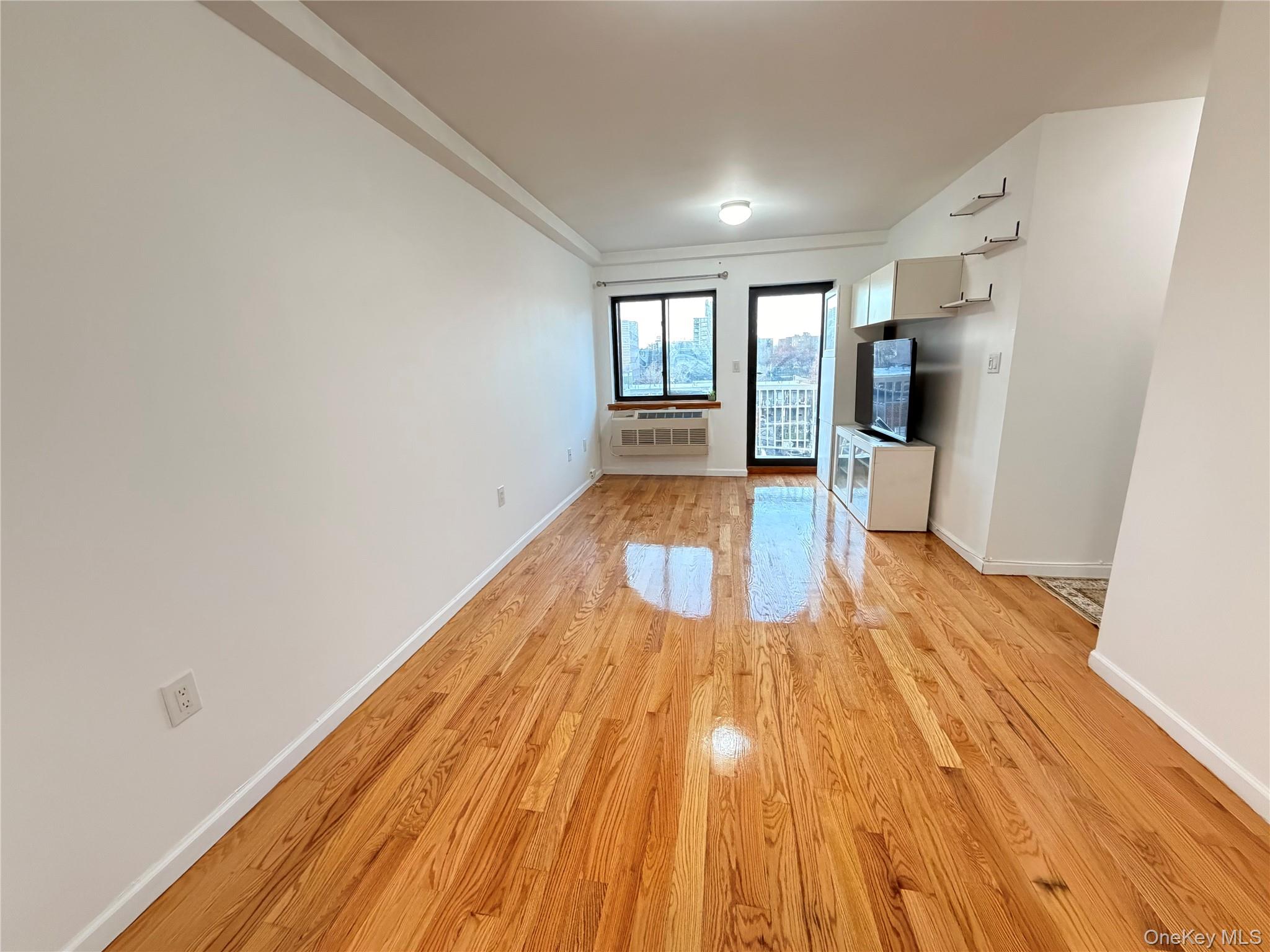 112-26 38th Avenue, Unit 4B Queens, NY 11368 - Photo 5 of 15 a view of empty room with wooden floor and fan