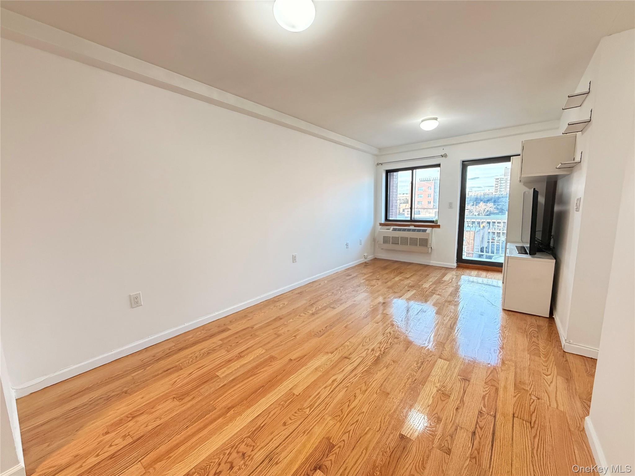 112-26 38th Avenue, Unit 4B Queens, NY 11368 - Photo 7 of 15 an empty room with wooden floor and natural light