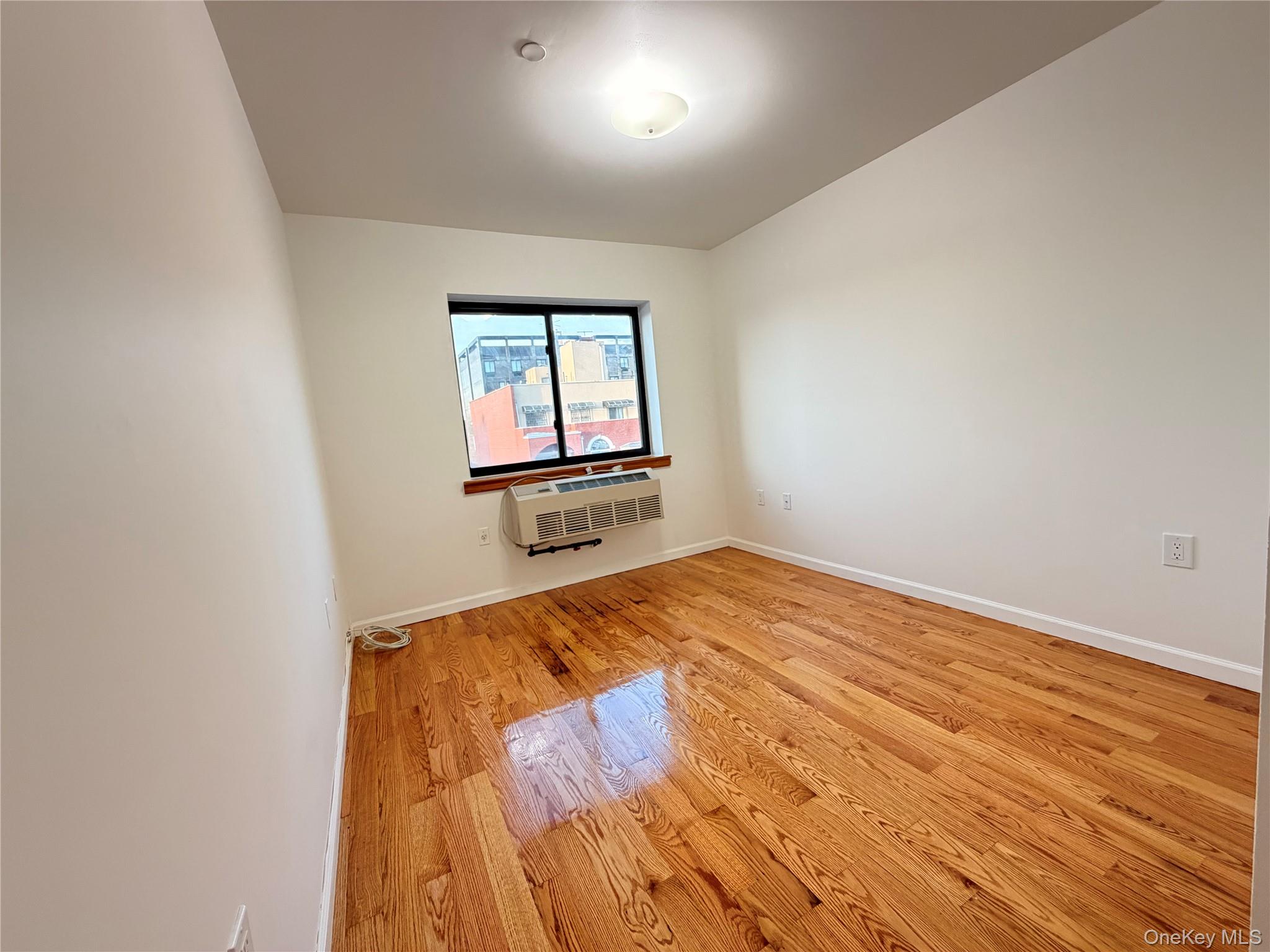 112-26 38th Avenue, Unit 4B Queens, NY 11368 - Photo 10 of 15 an empty room with wooden floor and windows
