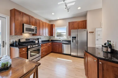 a kitchen with stainless steel appliances granite countertop a stove a sink dishwasher and a refrigerator with wooden floor