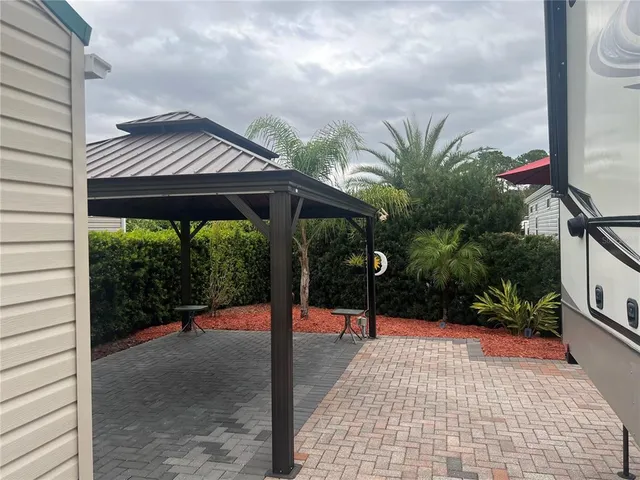 a backyard of a house with table and chairs under an umbrella