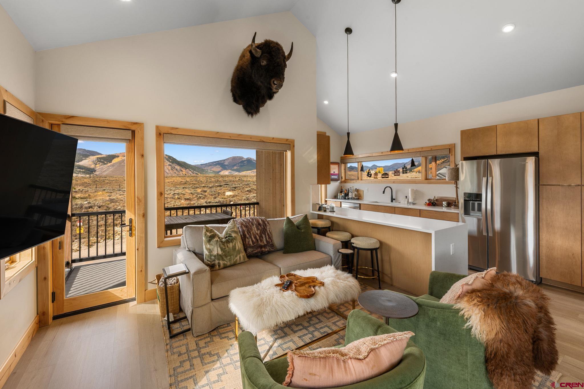 101 Elk Valley Road, Unit D Crested Butte, CO 81224 - Photo 11 of 37 a kitchen with a refrigerator a stove a sink and a dining table with wooden floor