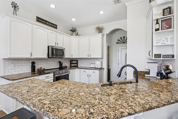 a kitchen with white cabinets and appliances