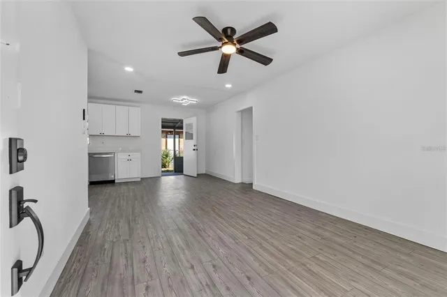 a view of an empty room with a kitchen and wooden floor