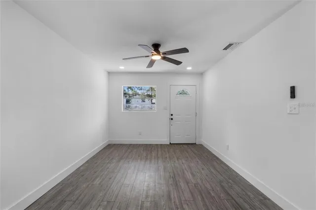 an empty room with a ceiling fan and wooden floor