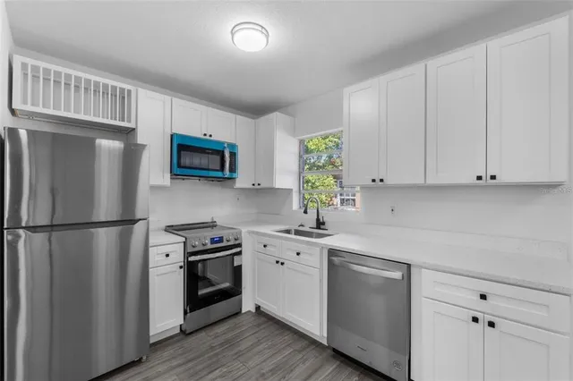 a kitchen with stainless steel appliances a refrigerator a stove a sink cabinets and a window