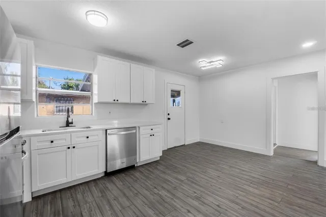 a large white kitchen with wooden floor and a sink