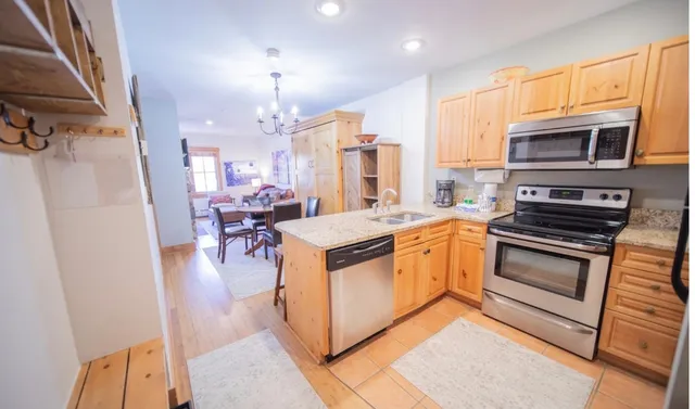 a kitchen with stainless steel appliances granite countertop a stove top oven a sink dishwasher a dining table and chairs with wooden floor