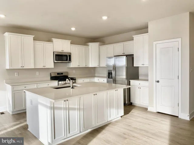a kitchen with white cabinets and stainless steel appliances