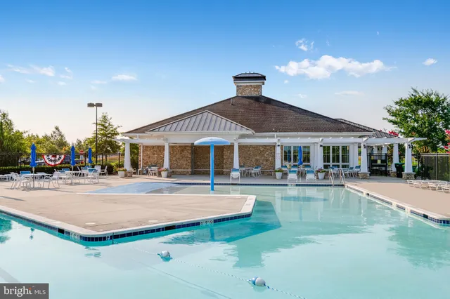 a view of a big house with pool and lawn chairs under an umbrella