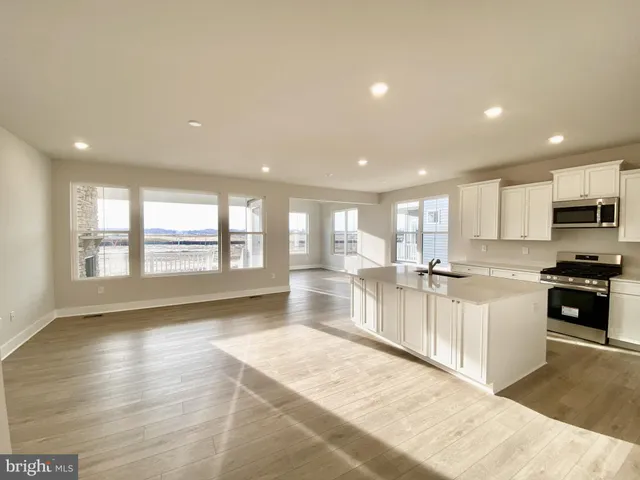 a large white kitchen with lots of counter top space a sink and stainless steel appliances