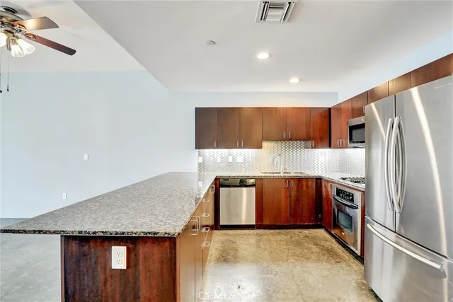 a kitchen with stainless steel appliances granite countertop a refrigerator a sink and a stove