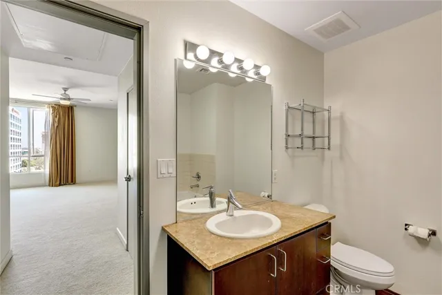 a bathroom with a granite countertop sink a toilet and a mirror
